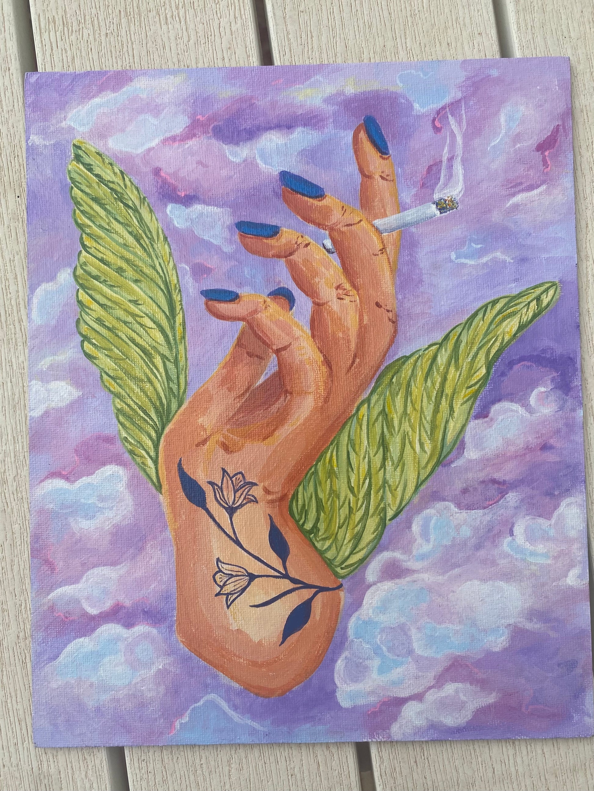 Cuadro pintado con acrílicos en un lienzo entablado de 27x22 cm realizado en 2023. Obra que evoca la rebeldía y la elegancia con símbolos de libertad como las alas sobre un cielo con nubes en colores azules, violetas y morados combinados con verdes amarillentos.